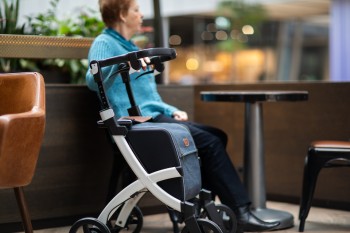 Woman with rollator sitting in a chair at a restaurant