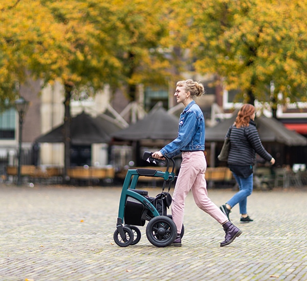Blond meisje dat met een moderne rollator in het oude stadscentrum loopt