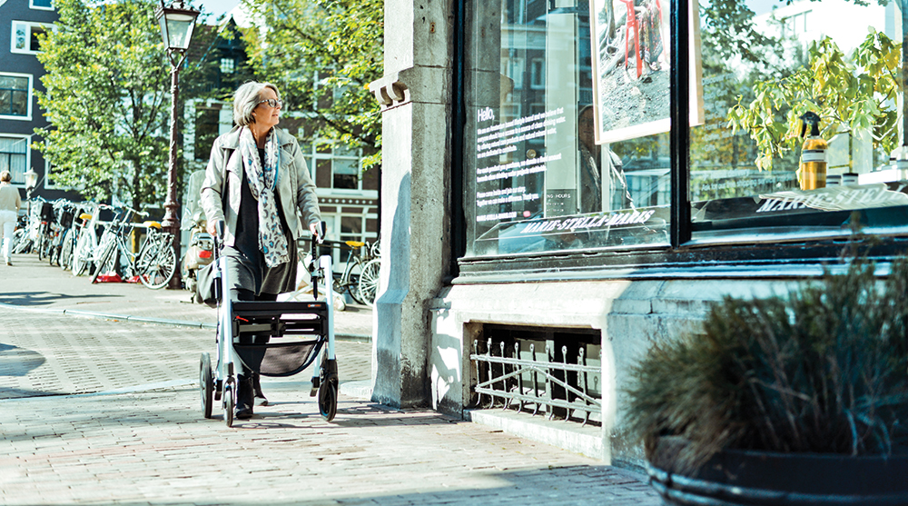 Woman walking with a rollator in a corona safe way on the streets of Amsterdam