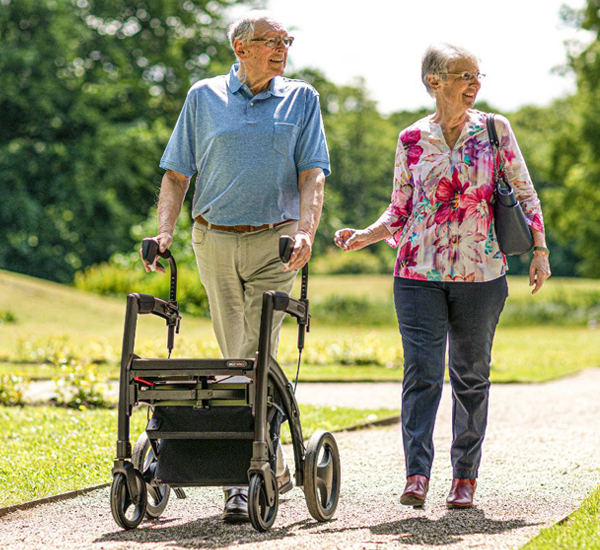 Man with mobility issues walks supported by a Rollz Motion Rhythm Parkinson rollator covered by health insurance